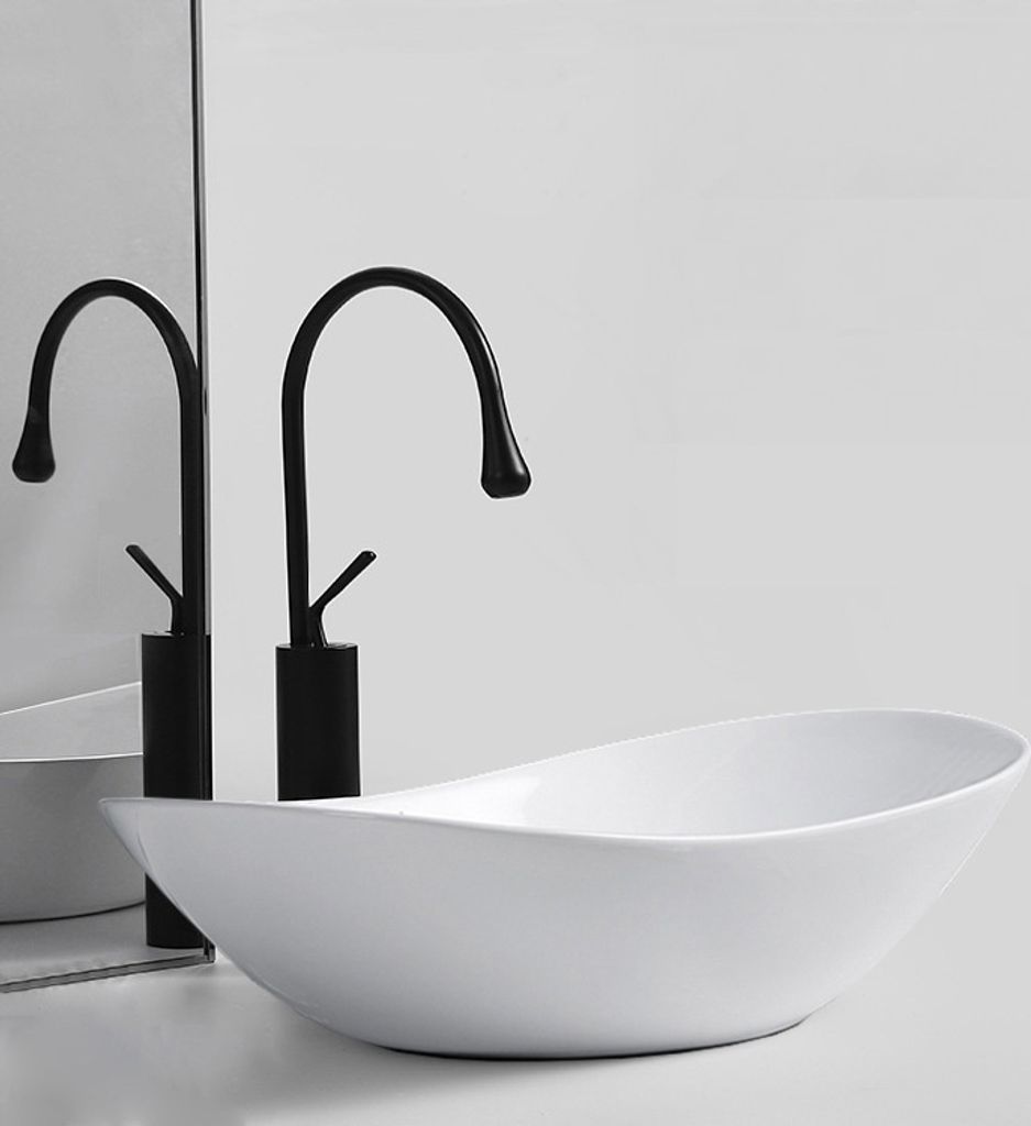 A white oval washbasin with two black faucets in front of a mirrored background.