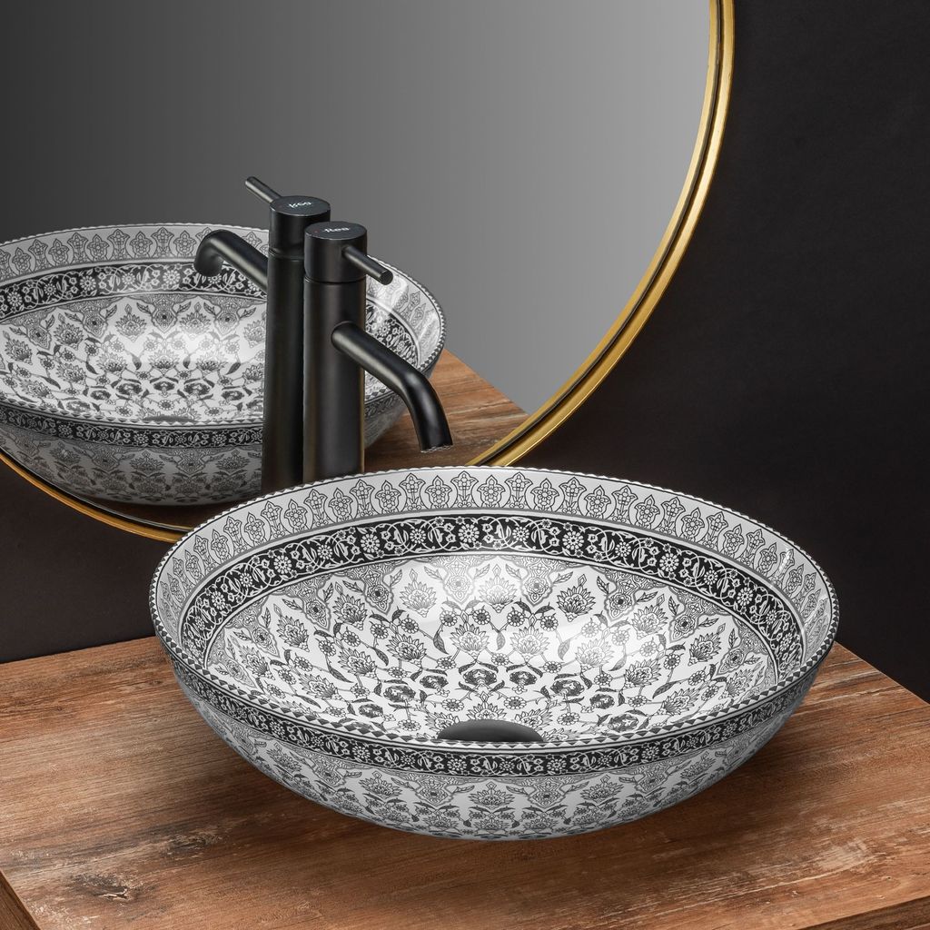 A decorative vessel sink with a black faucet and a gold-rimmed mirror in the background, placed on a wooden surface.