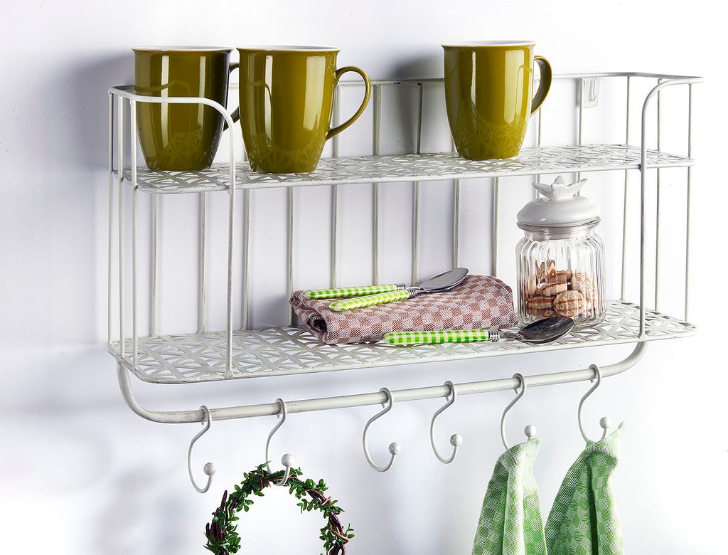 A white metal kitchen shelf with mugs, a jar of cookies, and folded towels.