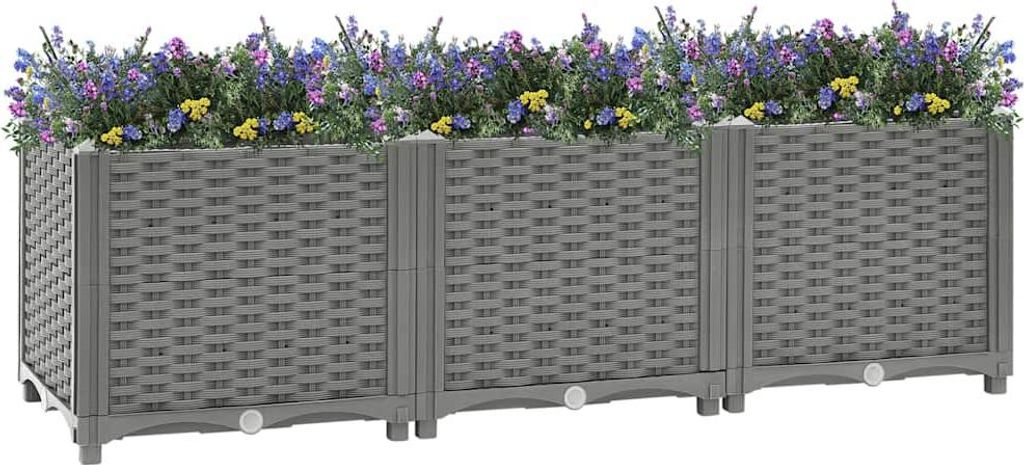 A long, gray, woven-textured planter box filled with purple and yellow flowers, set against a white background.