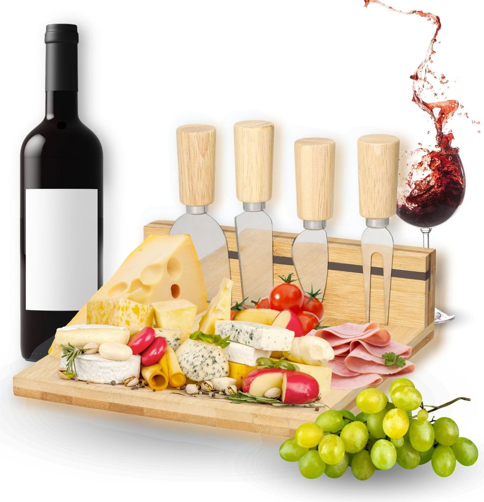 A cheese board set with various cheeses, meats, grapes, tomatoes, and cheese knives, along with a bottle of red wine and a splash of wine in a glass.
