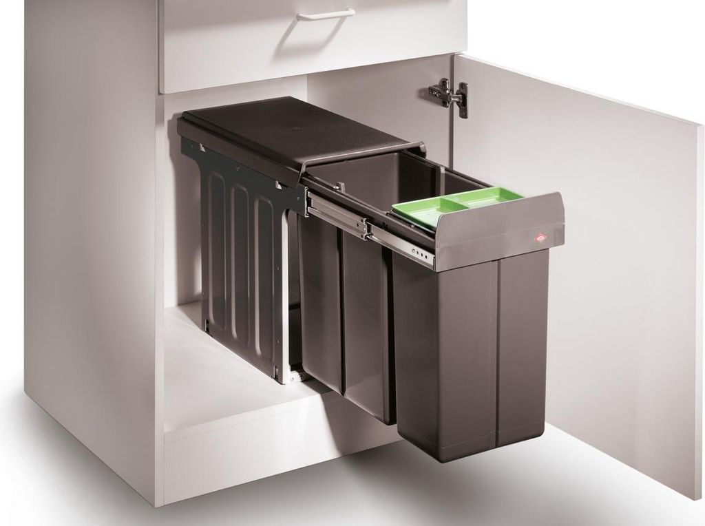 A pull-out kitchen bin system with multiple compartments inside a cabinet.