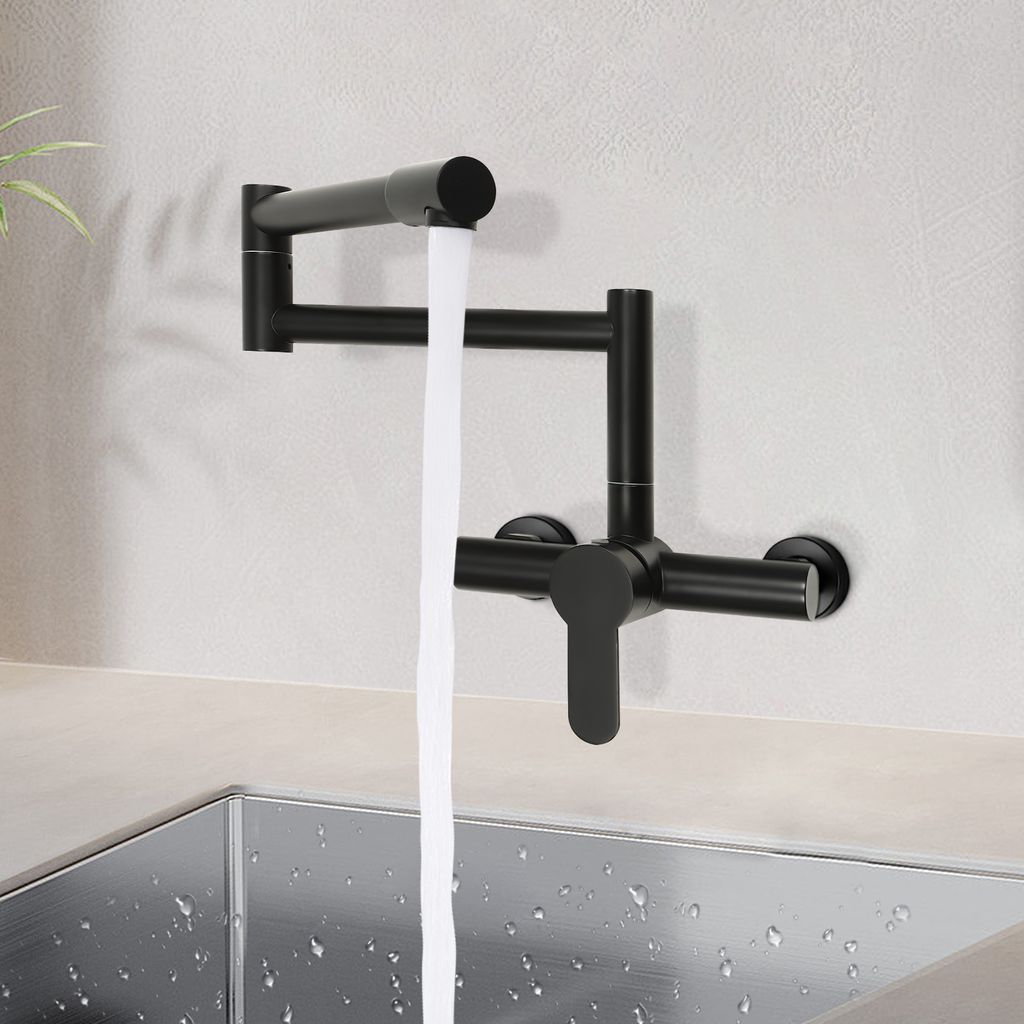 A black wall-mounted kitchen faucet with water flowing into a stainless steel sink.