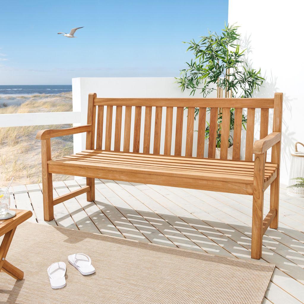 A wooden garden bench on a deck overlooking a beach.