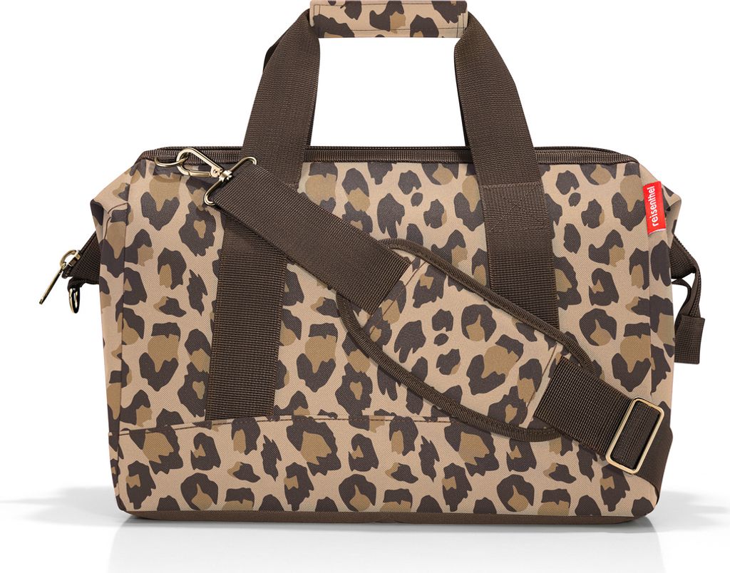 A leopard print duffel bag with brown straps and a detachable shoulder strap.