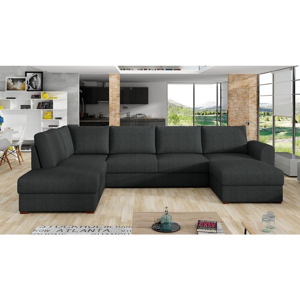 A modern living room with a large U-shaped sectional sofa, a coffee table, and a view of a natural landscape through large windows.
