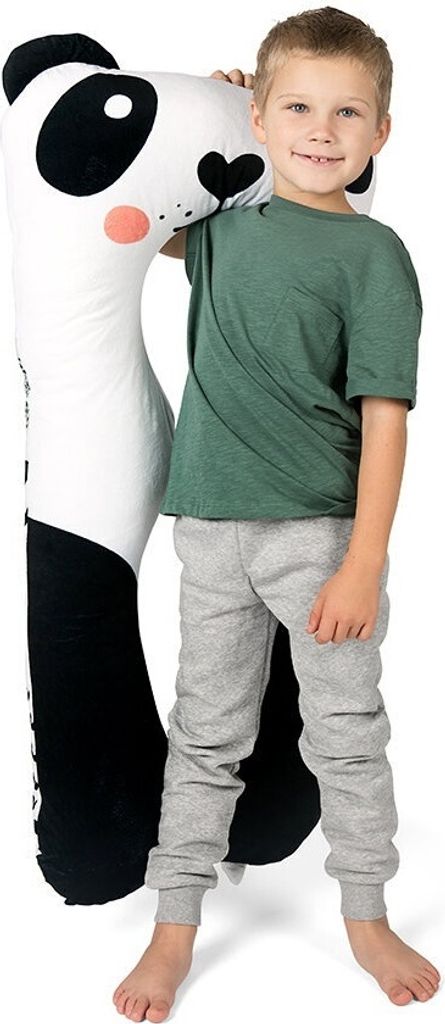 A young boy stands next to a large panda plush toy.