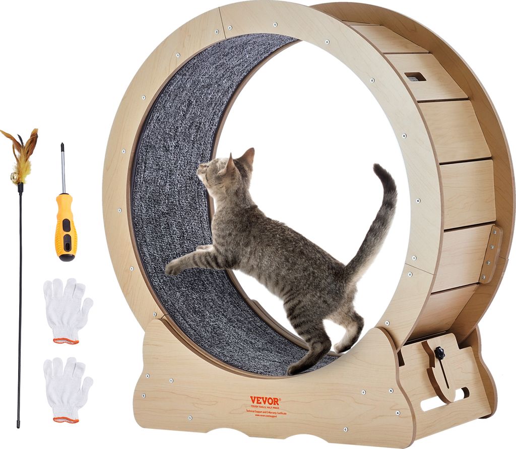 A cat is running on a large wooden wheel designed for cats, with accessories like a feather wand, screwdriver, and gloves laid out next to it.