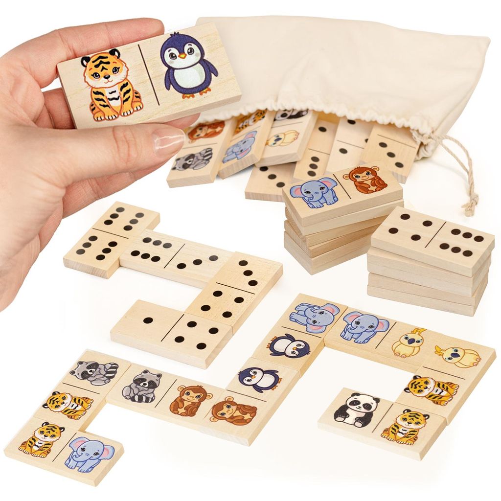 A hand holding a domino tile with a tiger and penguin, with other domino tiles and a drawstring bag in the background.