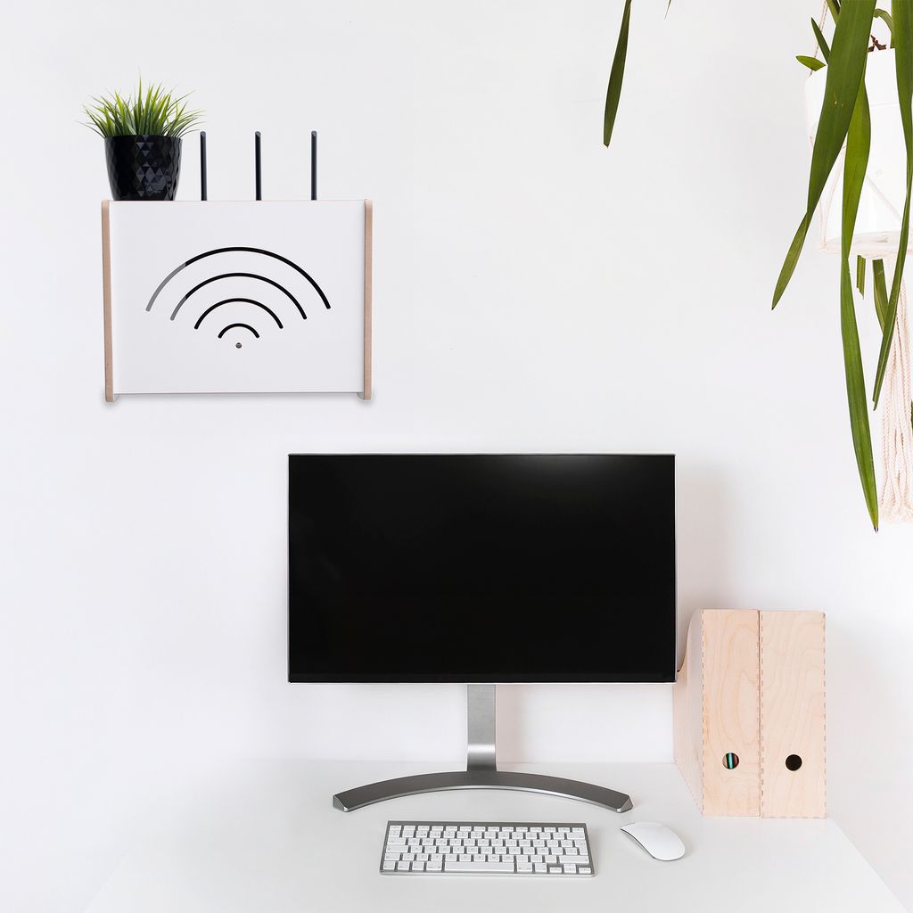 A white wall-mounted router storage box with a plant and router antennas on top, and a computer monitor and keyboard below.