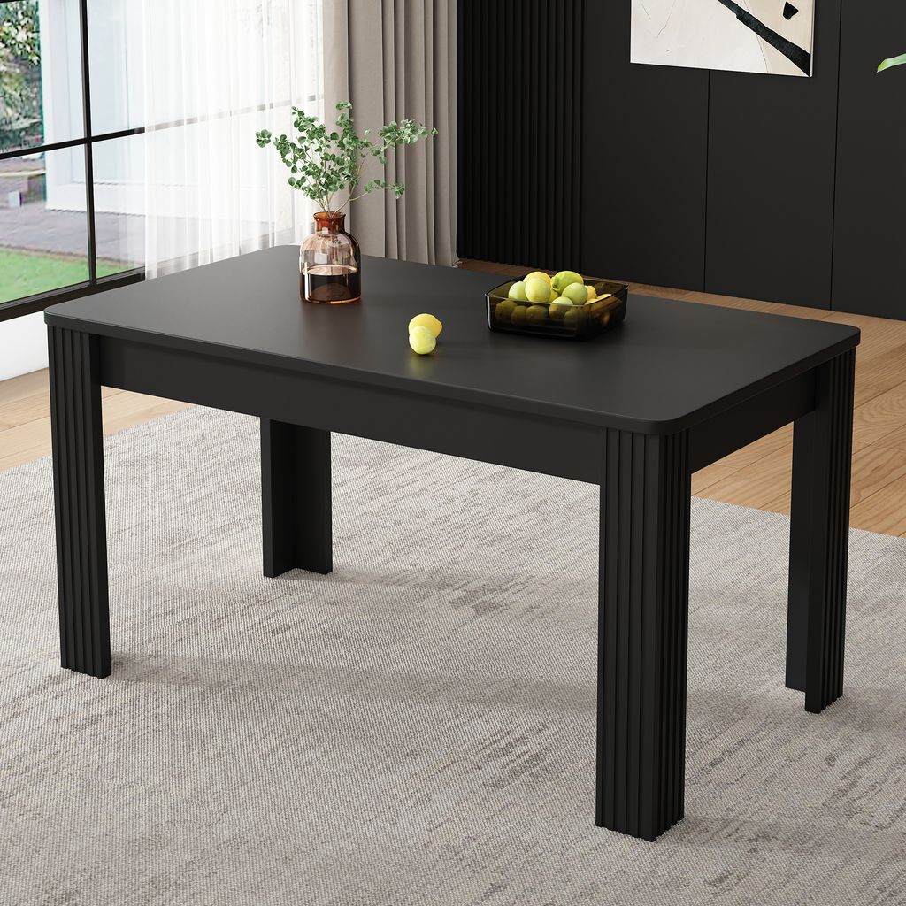 A black rectangular dining table with fluted legs is shown in a well-lit room with a light gray rug and a window in the background.