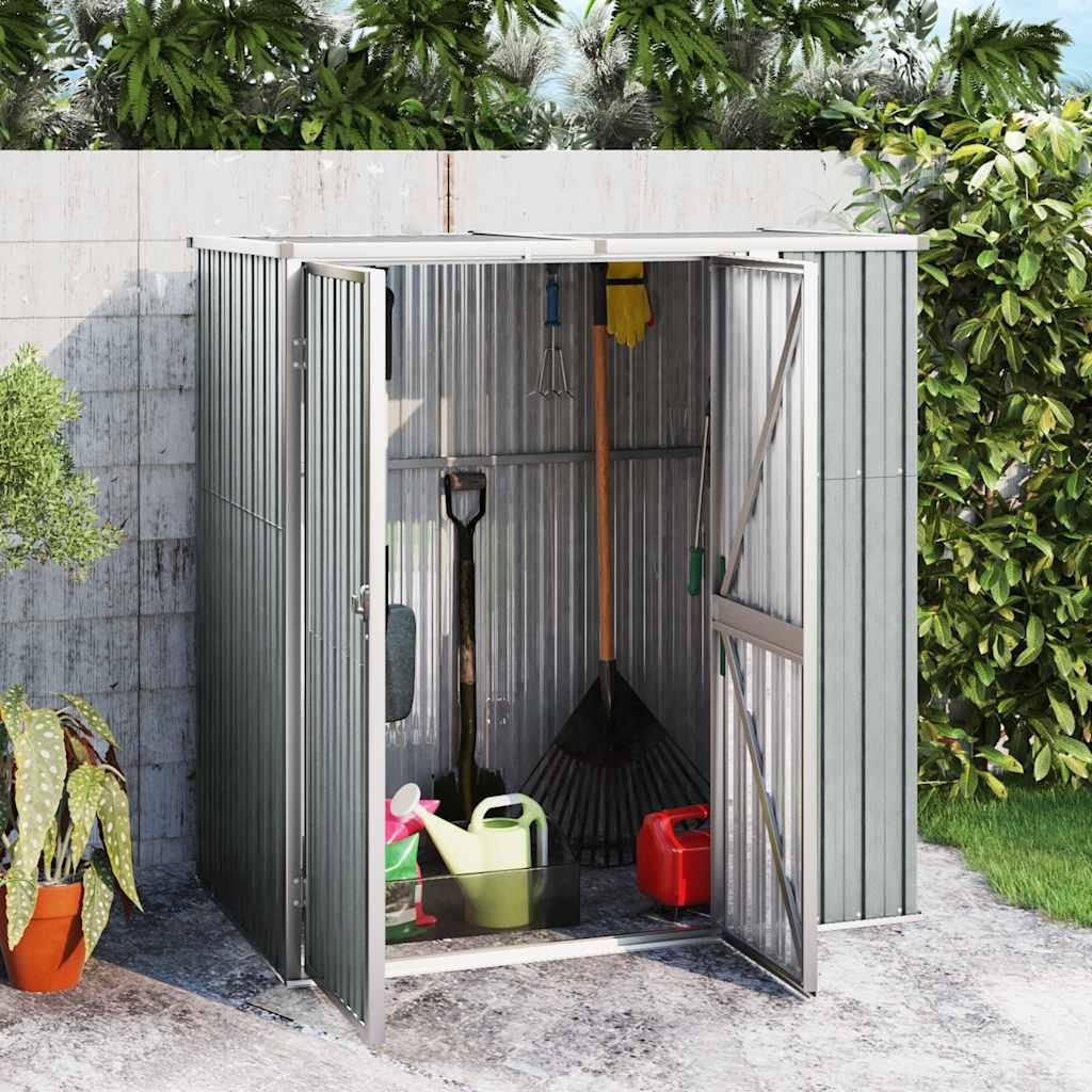 A metal garden shed filled with gardening tools and supplies, set against a concrete wall and lush greenery.