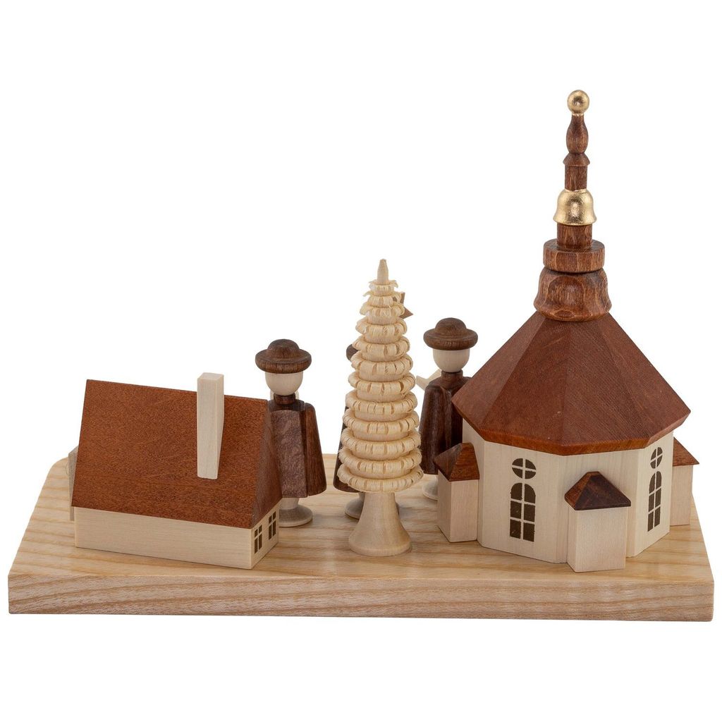Ein kunstvoll gestalteter Kerzenhalter zeigt ein kleines Dorf mit einer Kirche einem Baum und zwei Figuren auf einer Holzplatte