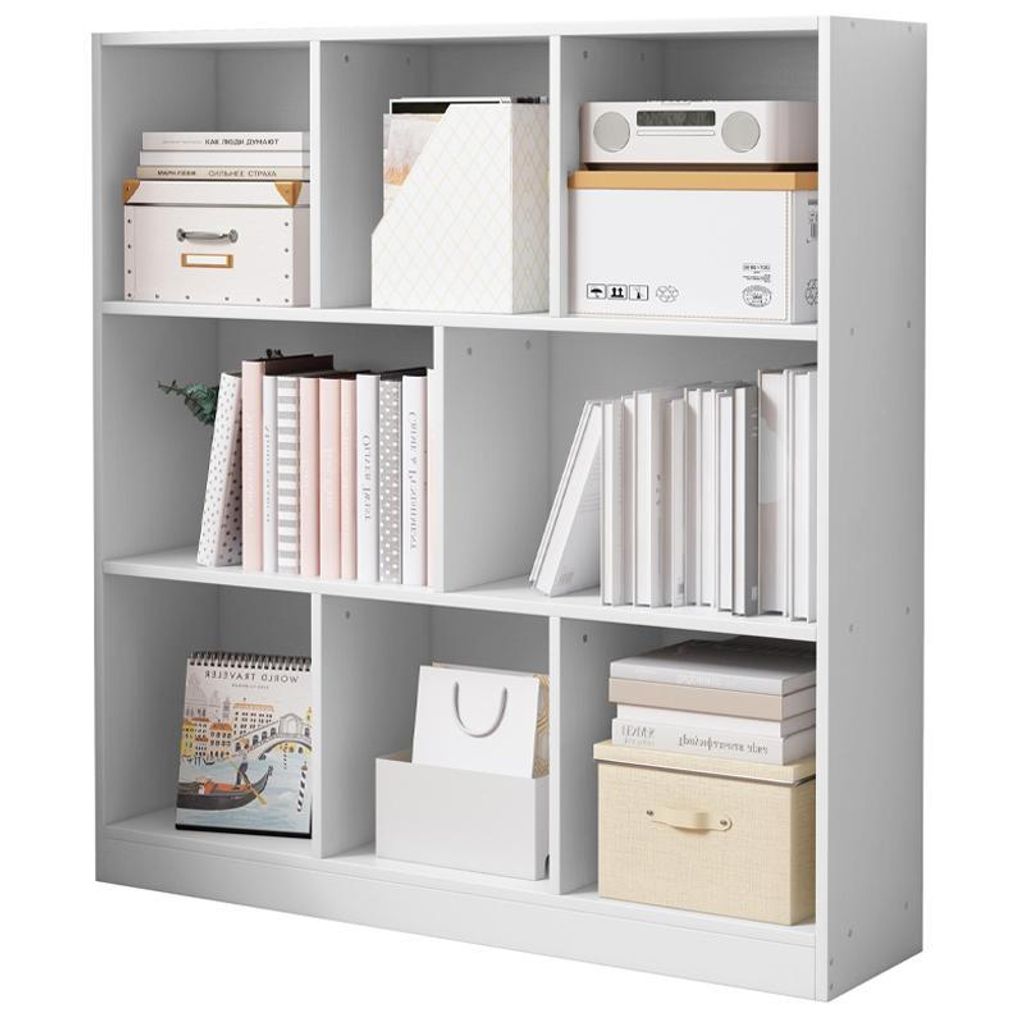 A white cube bookshelf filled with books, boxes, and a calendar.