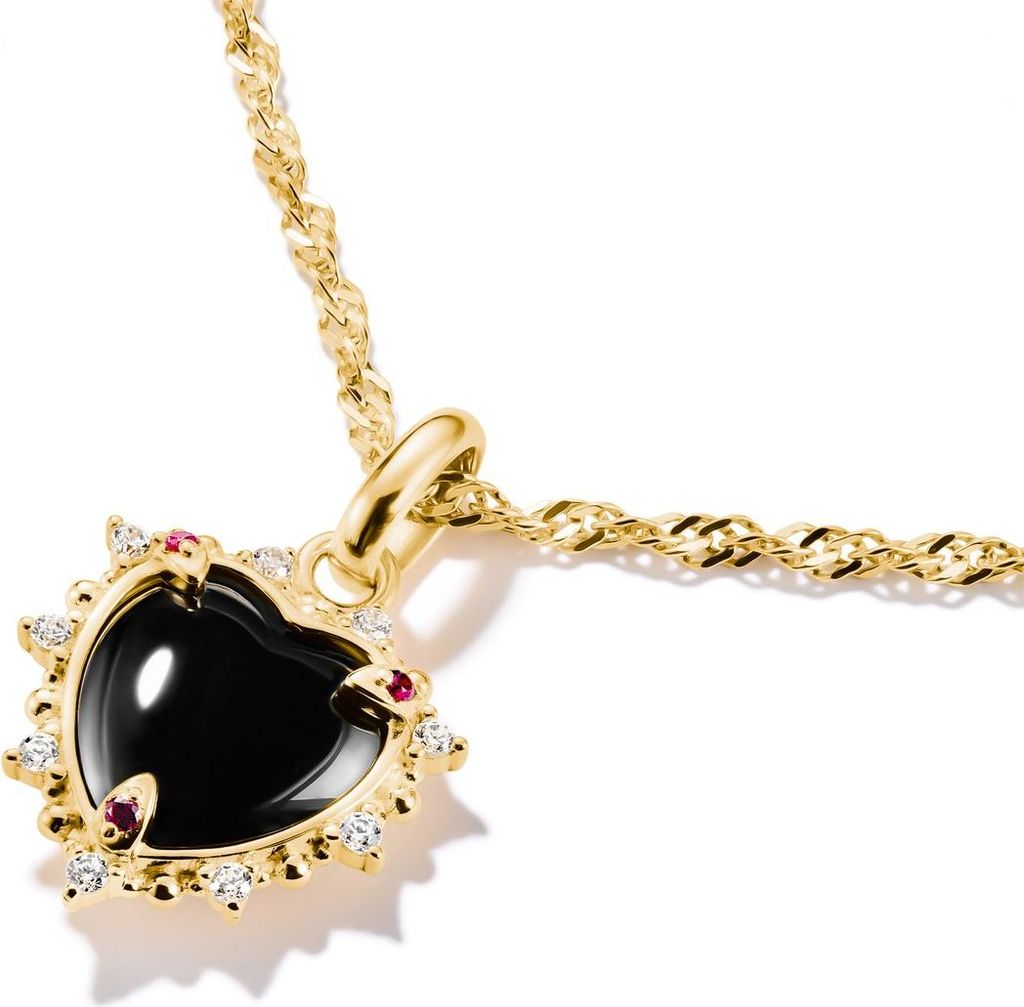 A close-up shot of a heart-shaped pendant necklace with a black stone, surrounded by small red and white stones, on a gold chain.