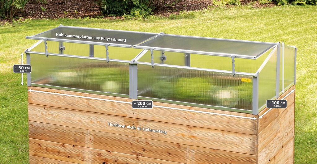 A wooden raised garden bed with a clear polycarbonate greenhouse cover.