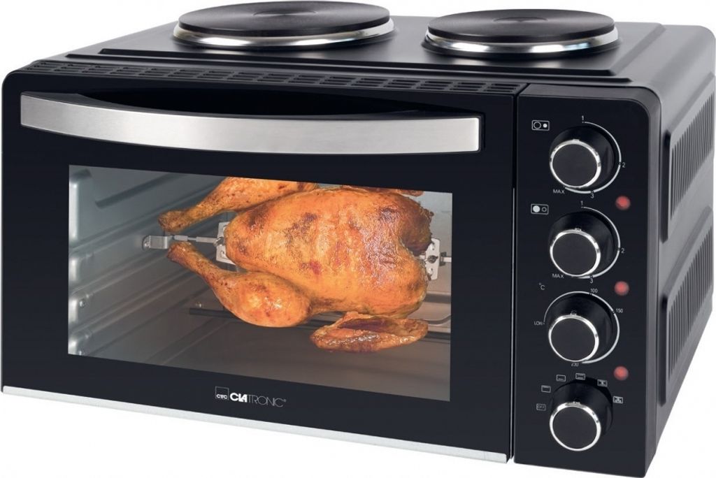 A black mini oven with a rotisserie chicken inside, set against a white background.