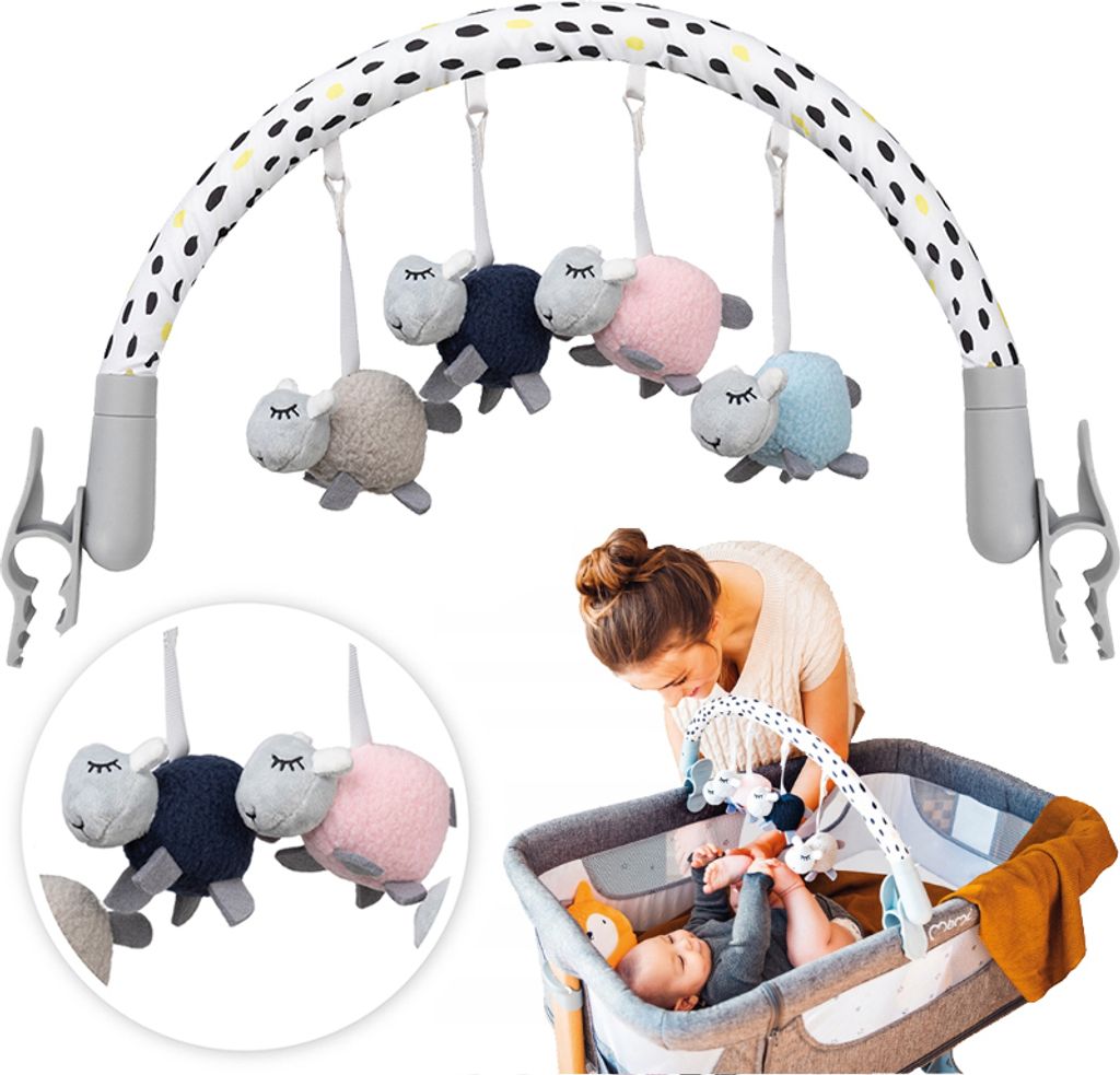 A baby mobile with sheep toys is attached to a crib, with a woman looking at the baby.