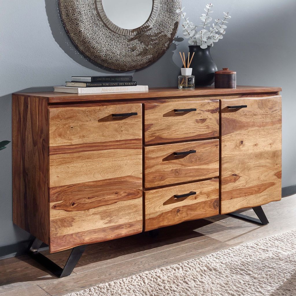 A wooden sideboard with drawers and doors, set against a gray wall and on a rug.