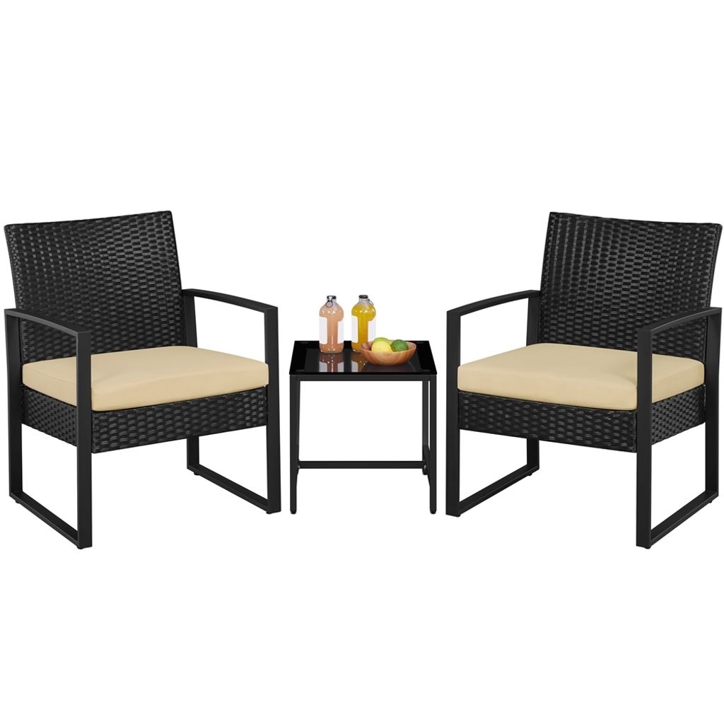 A black rattan-effect outdoor furniture set with beige cushions, consisting of two chairs and a small table with drinks and fruit.