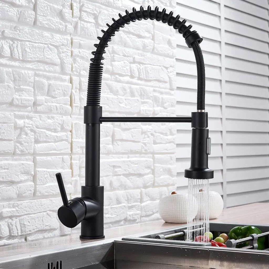 A black kitchen faucet with a pull-down sprayer is shown in use over a sink.