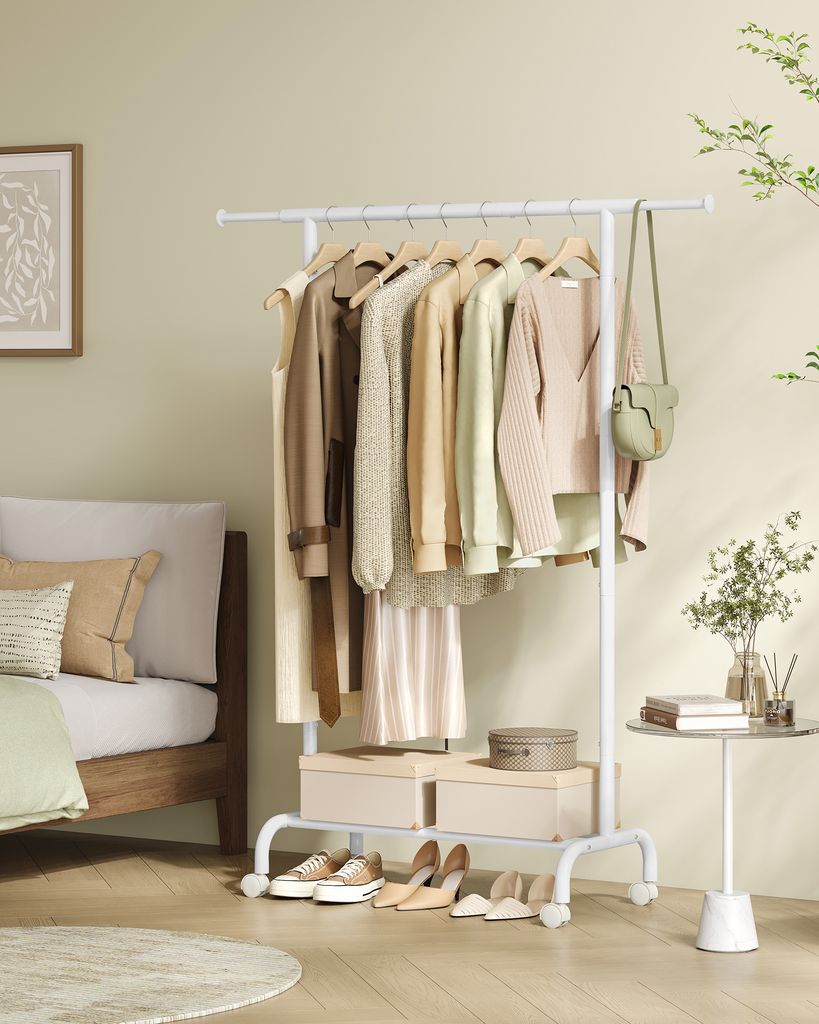 A white garment rack with clothes and accessories is placed next to a bed in a bedroom.