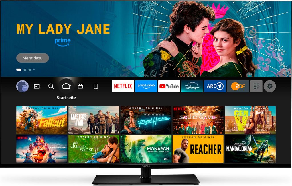 A television screen displaying a streaming service interface with various show thumbnails and app icons.