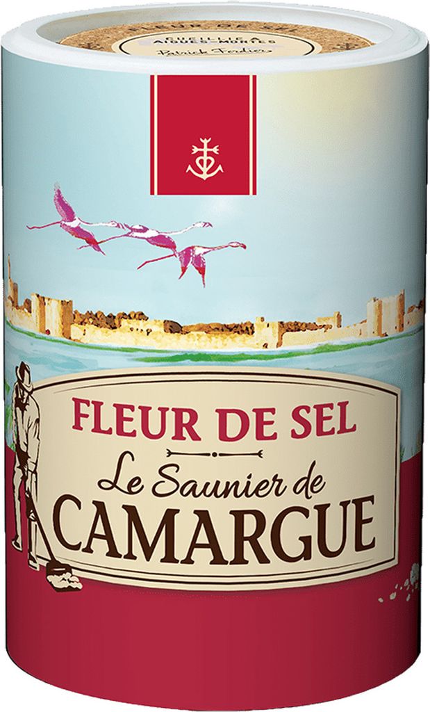 A cylindrical container of Fleur de Sel with a scenic illustration of flamingos flying over a walled city.
