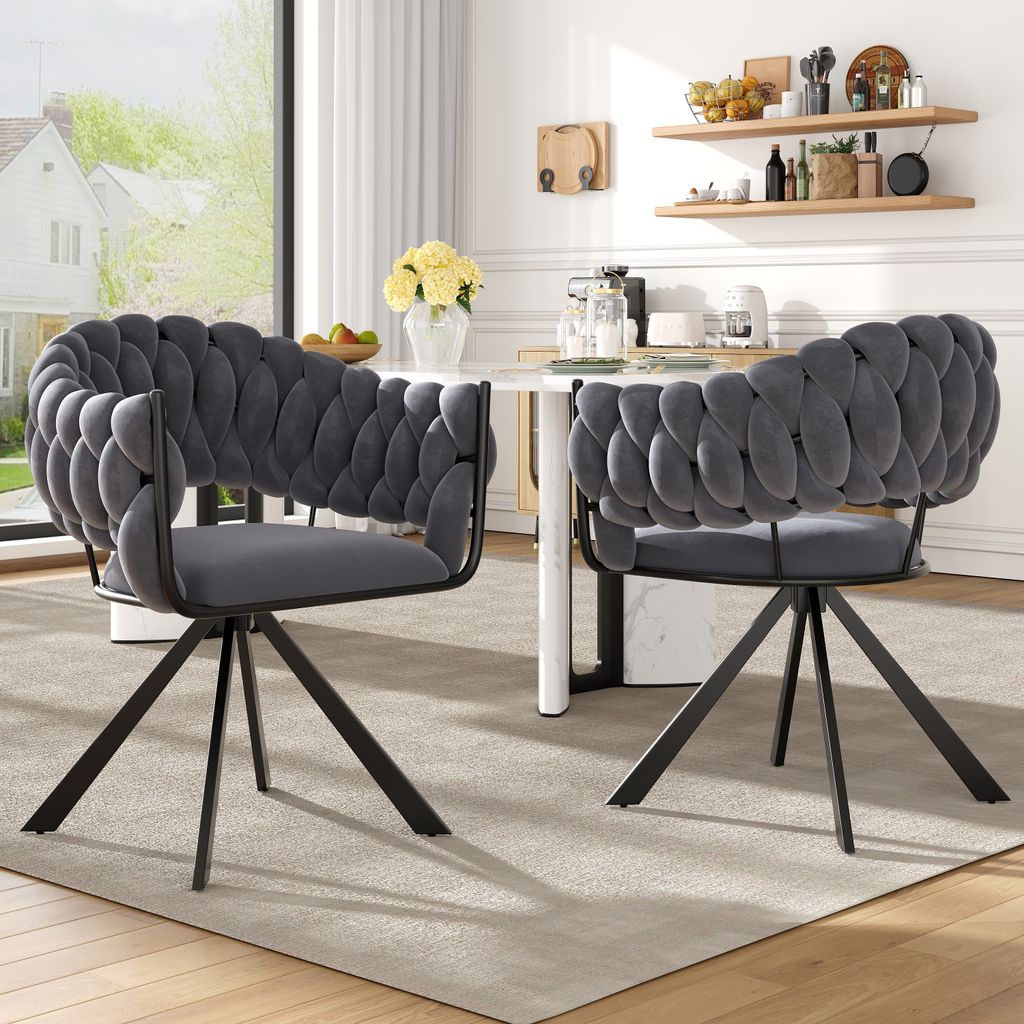 Two gray velvet dining chairs with braided backs are placed around a white dining table in a well-lit room.