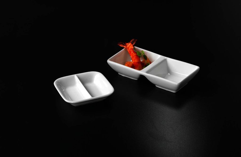 Two white ceramic dip bowls on a black background. One bowl is empty, the other contains a shrimp and garnish.