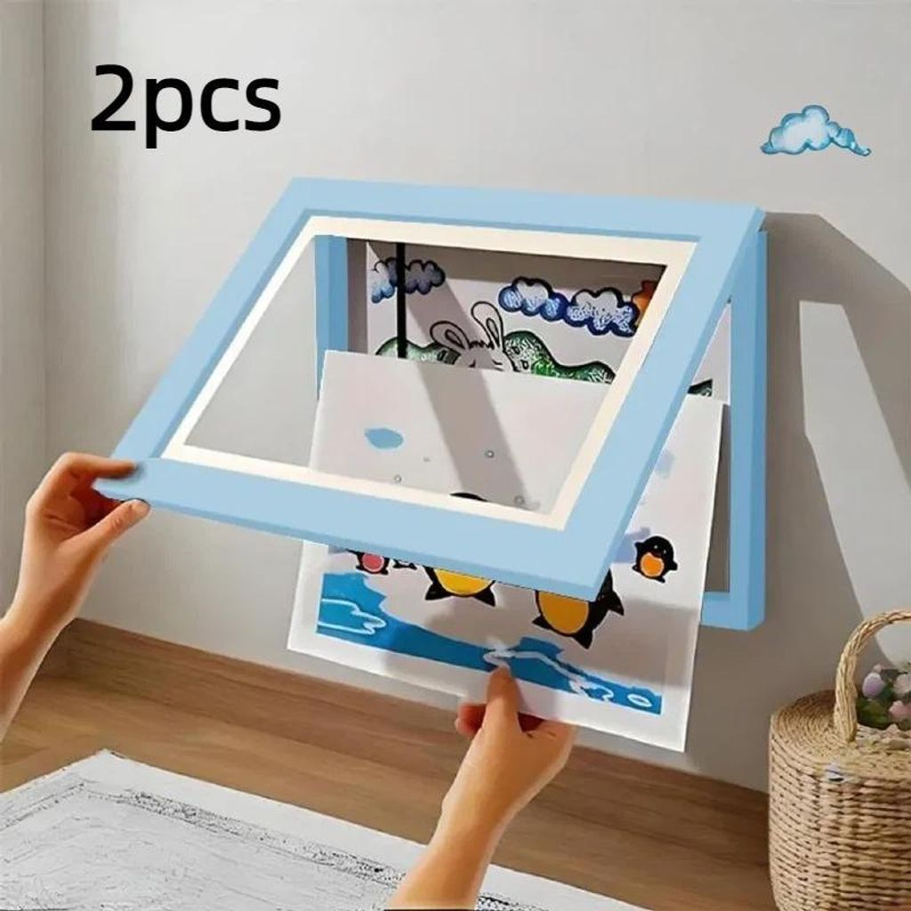 Hands are shown inserting artwork into a light blue picture frame mounted on a wall.