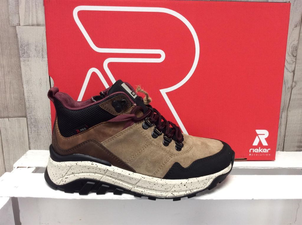 A shoe is displayed in front of a red box with a large white 'R' logo.