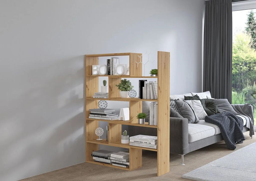 A wooden bookshelf filled with books and decorative items, placed next to a sofa in a living room.
