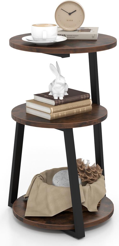A three-tiered round side table with a rustic brown wood finish and black metal legs, decorated with a coffee cup, books, a ceramic rabbit figurine, and decorative items in a basket.
