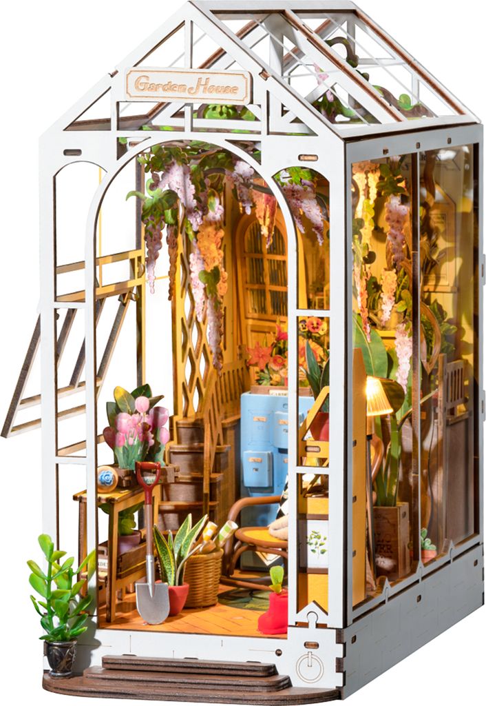 A miniature model of a greenhouse with plants and gardening tools inside.