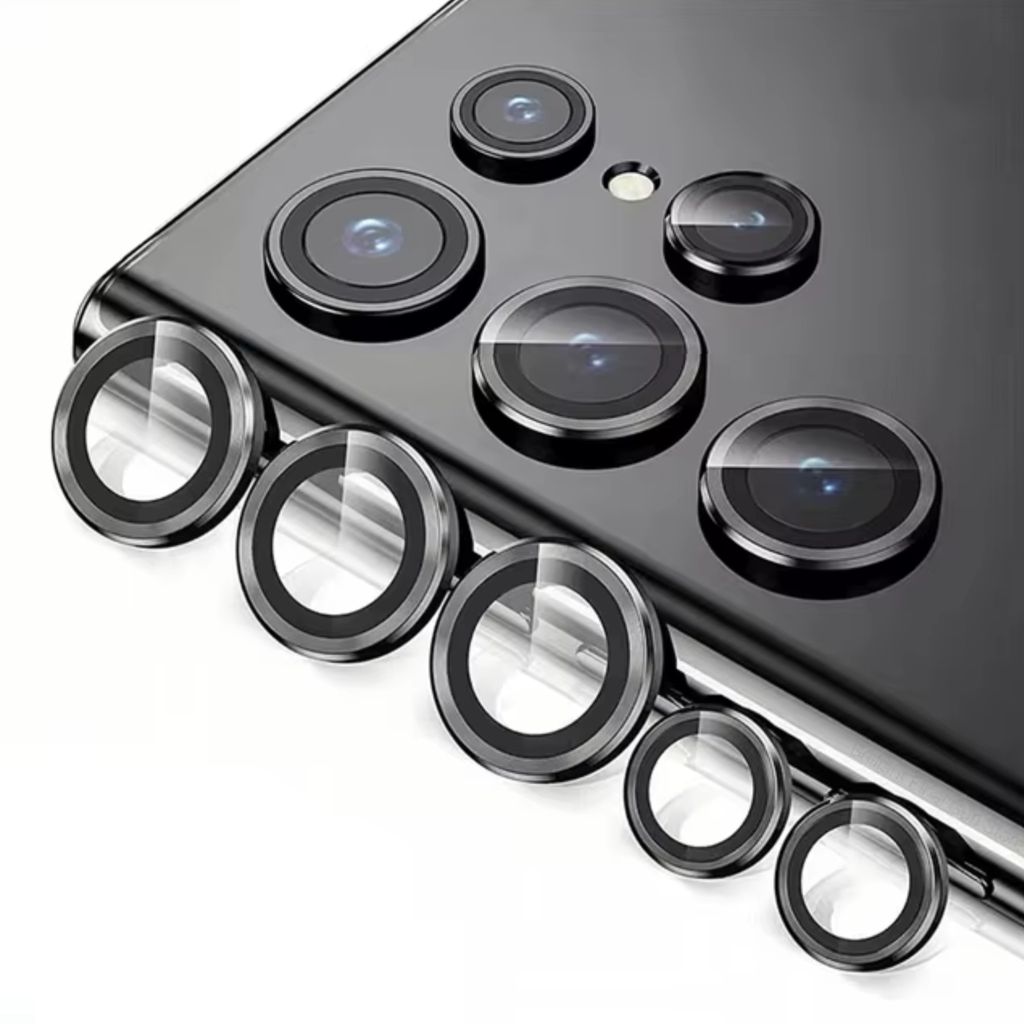 A close-up view of multiple camera lens protectors arranged on a surface, with a portion of a smartphone visible in the background.