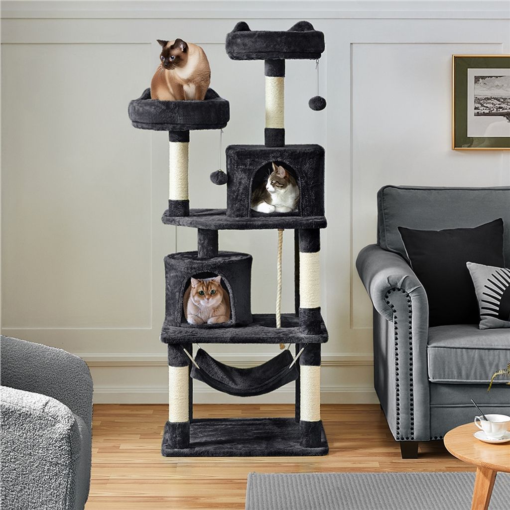 A multi-level cat tree with three cats is shown in a living room setting next to a sofa.
