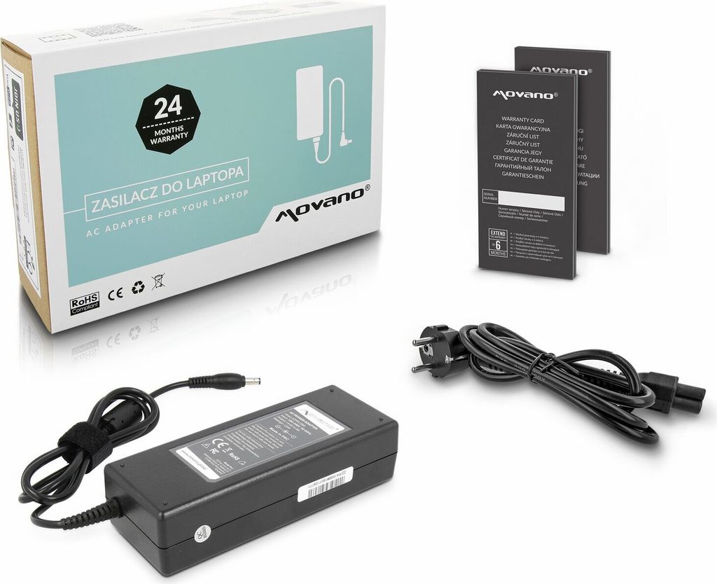 A product shot of a laptop AC adapter and its accessories, including the box, warranty cards, and cables, arranged on a white background.