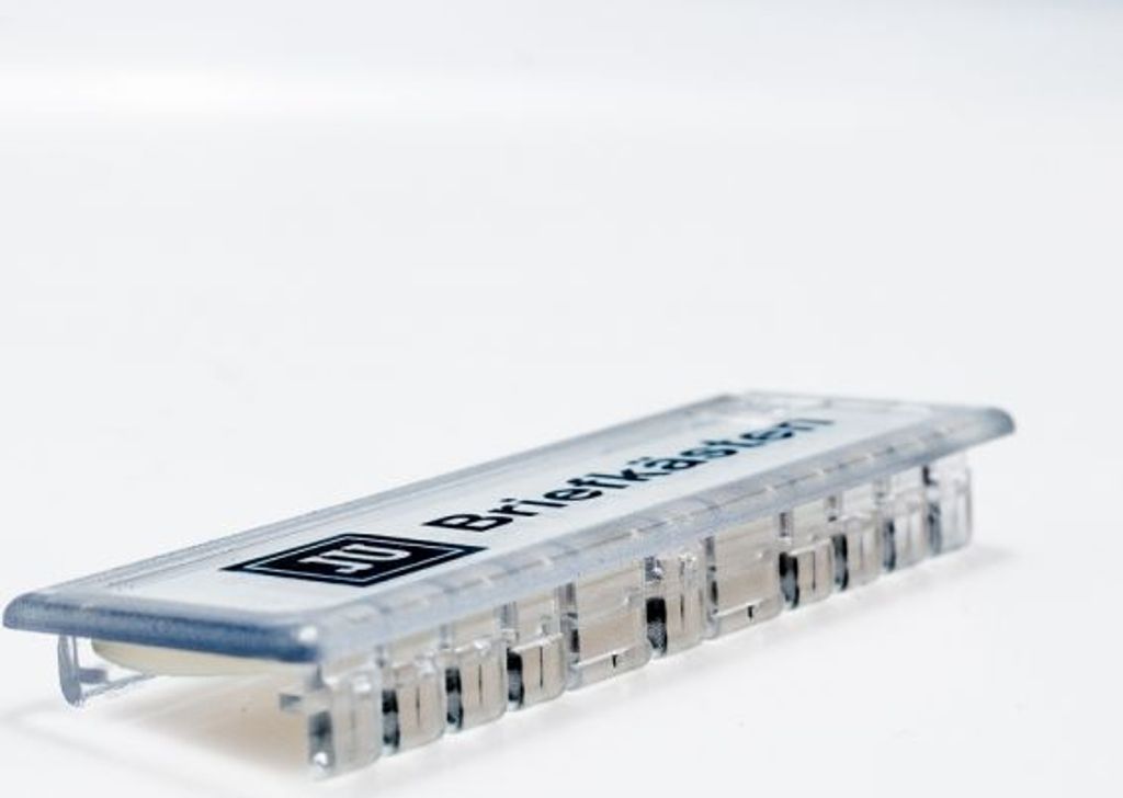 A close-up shot of a clear name tag with black text and a logo on a white background.