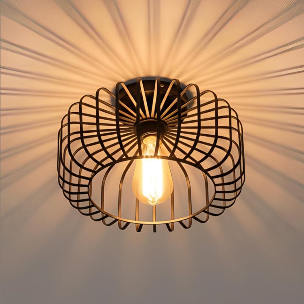 A black metal cage-style ceiling light fixture with an exposed Edison bulb, casting dramatic shadows on a white ceiling.
