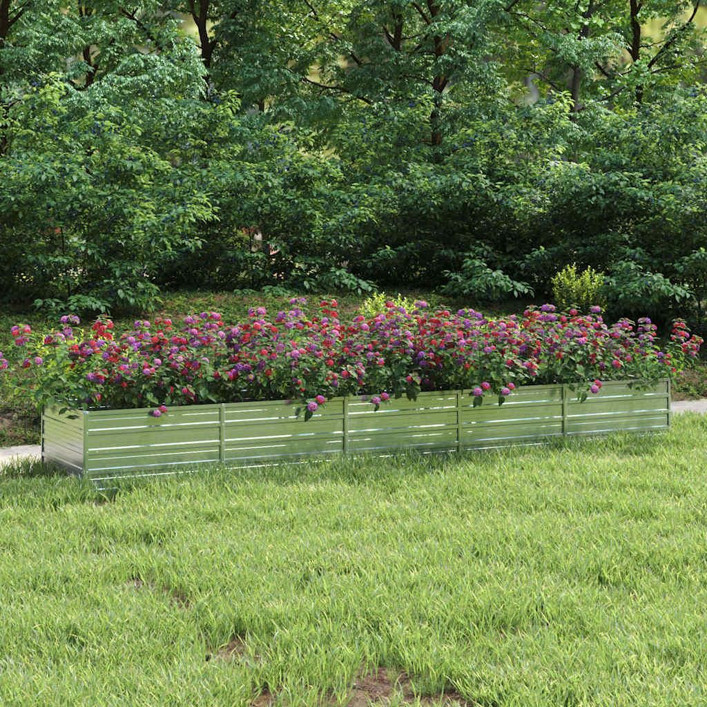 A raised garden bed filled with flowers in a grassy yard with trees in the background.