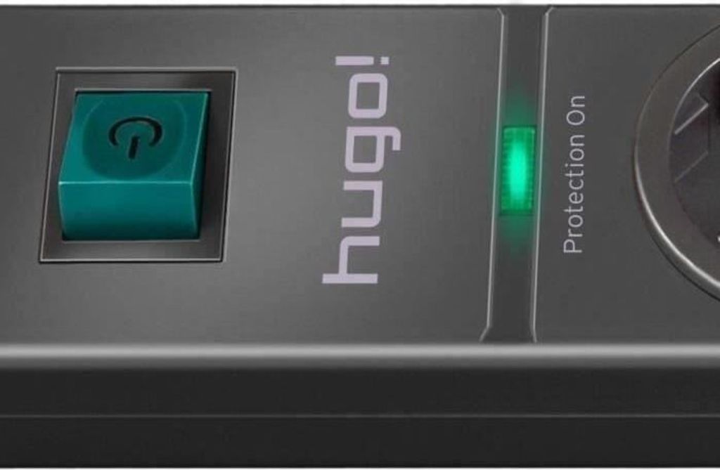 A close-up view of a black power strip with a green power button and a green indicator light.