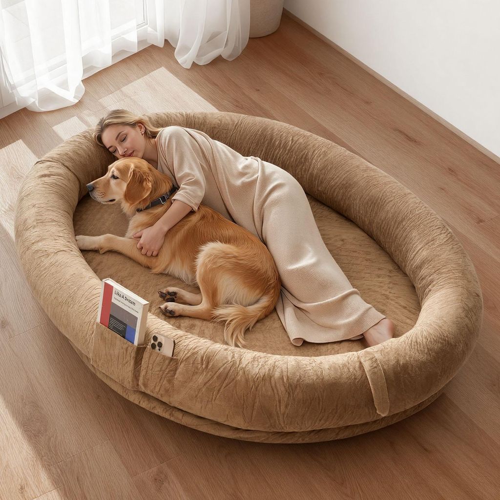 A woman and her dog are sleeping together on a large oval dog bed.