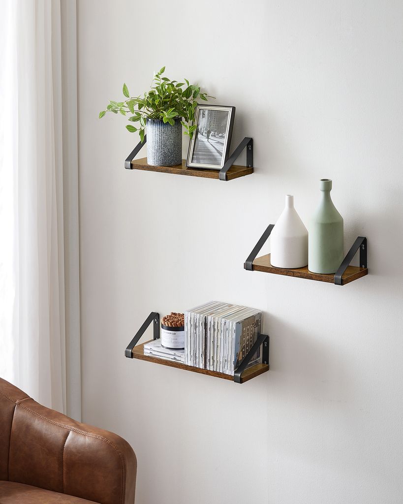 Three wooden shelves mounted on a white wall, each with decorative items.