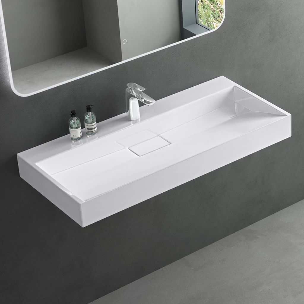 A modern white rectangular wall-mounted sink with a chrome faucet and two soap dispensers, set against a dark gray wall.