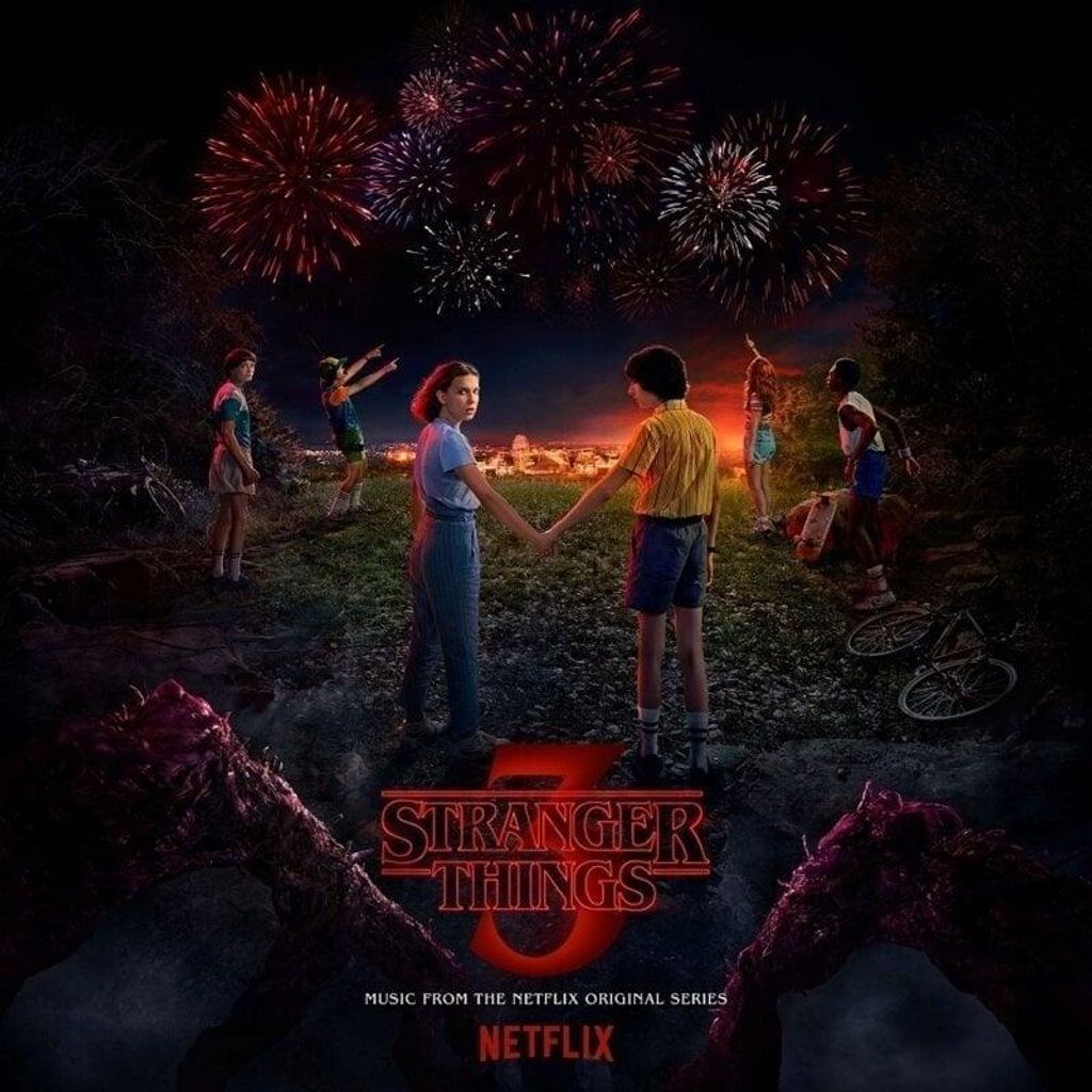 Children and teenagers stand on a hill overlooking a town at night, with fireworks in the sky. The Stranger Things 3 logo is prominent.