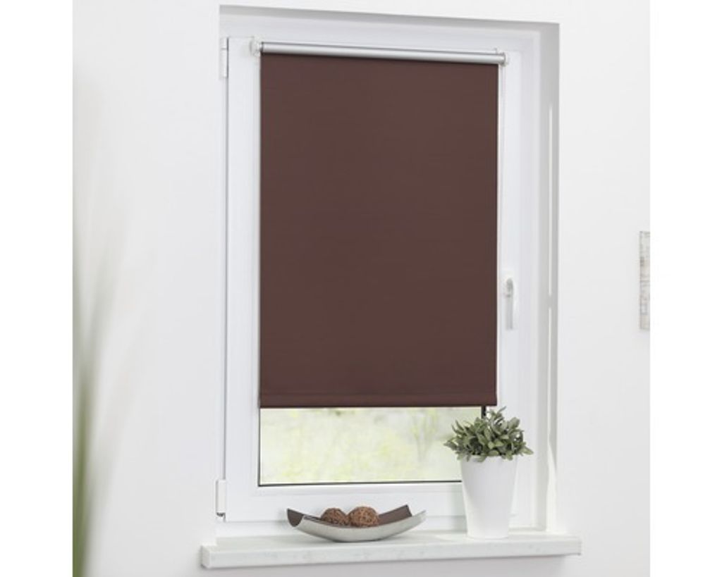 A brown roller blind is installed on a white window frame.