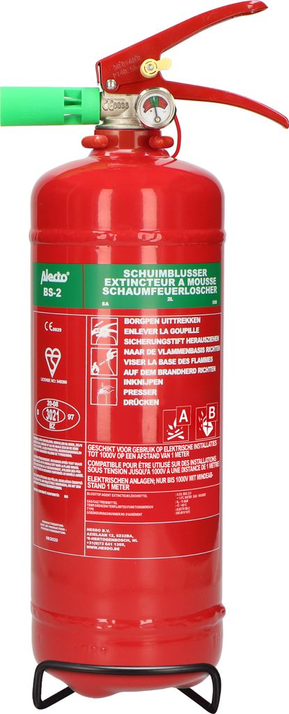 A red fire extinguisher with a green nozzle and a pressure gauge, standing on a black metal stand.
