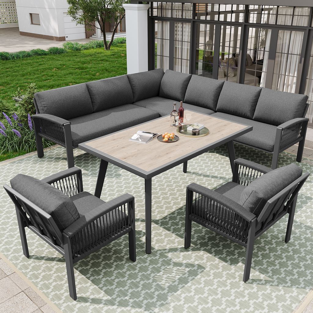 An outdoor patio set with a sectional sofa, two chairs, and a coffee table, set on a patterned rug.