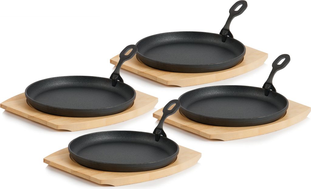 Four cast iron serving pans with wooden bases are arranged in a staggered pattern on a white background.
